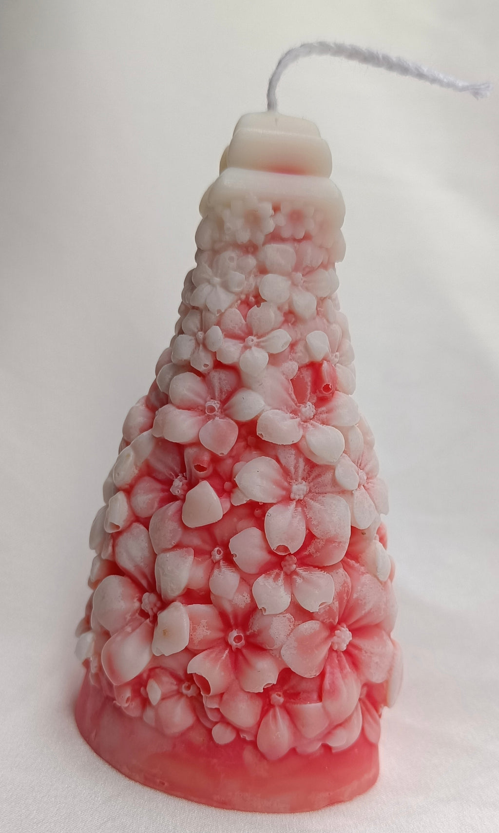 Vela decorativa Árbol de Navidad con diseño floral y base rosa, ideal como regalo artesanal para fiestas.