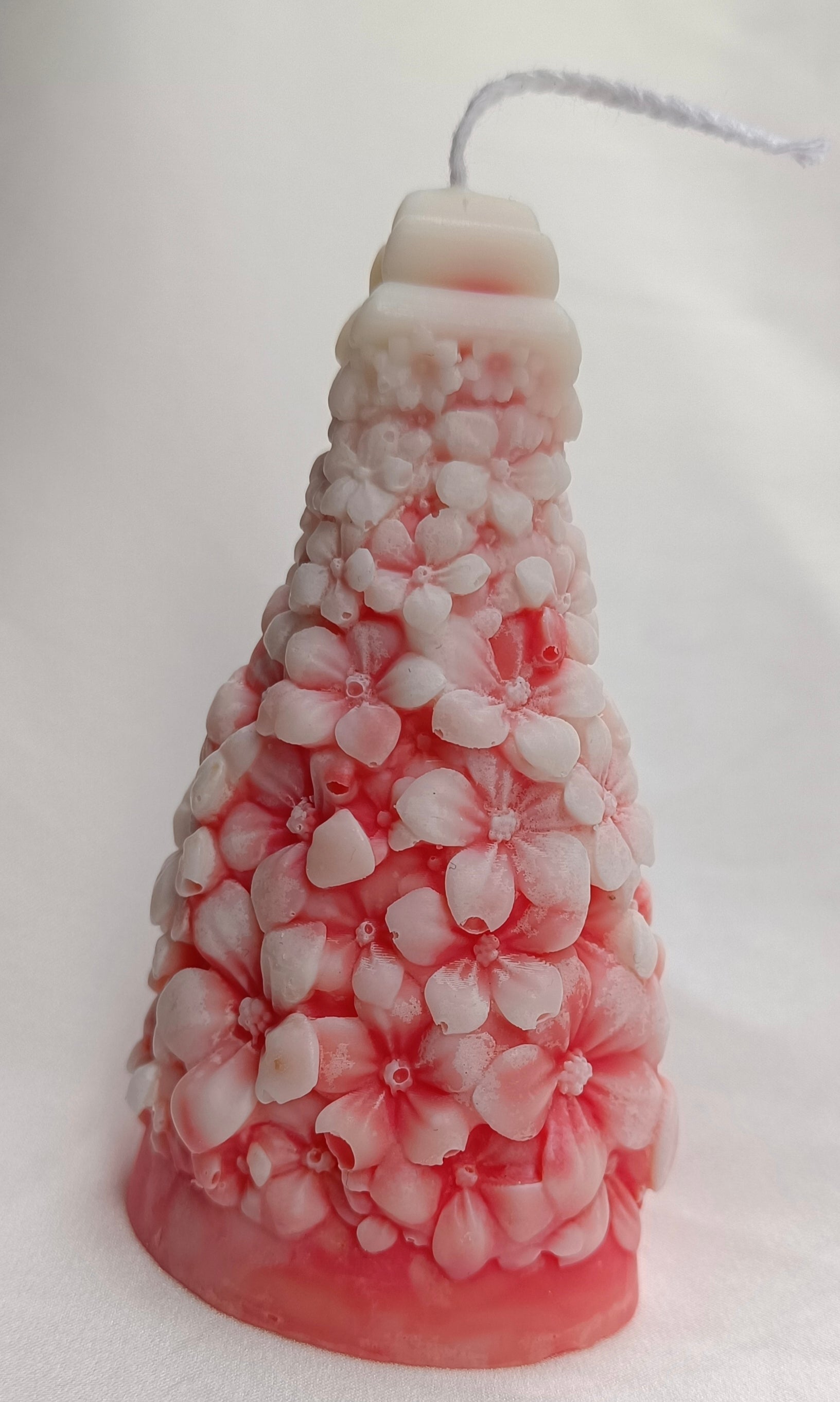 Vela decorativa Árbol de Navidad con diseño floral y base rosa, ideal como regalo artesanal para fiestas.