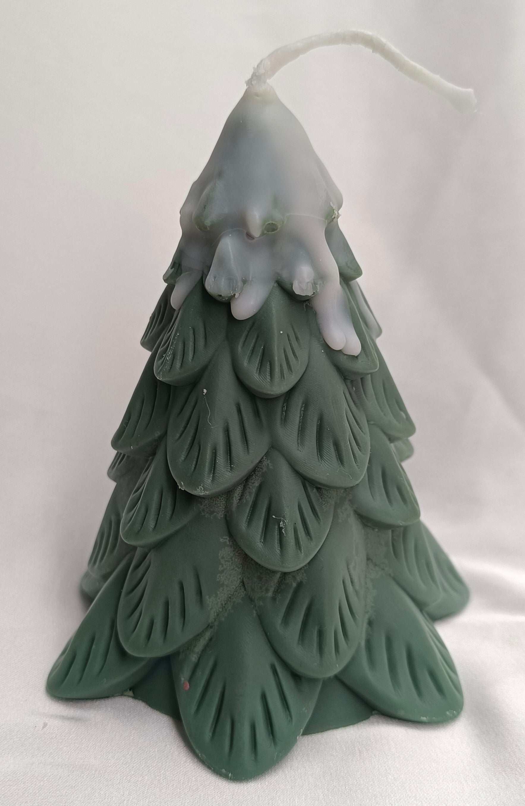 Vela de Navidad en forma de pino nevado, con textura de ramas y color verde oscuro, para un ambiente invernal.