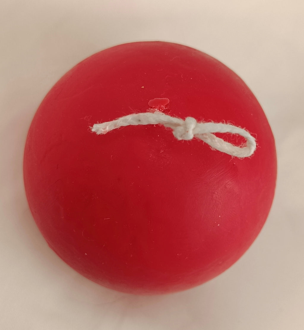 Vela artesanal Bola de Navidad roja con mecha anudada para colgar, hecha a mano con cera natural.