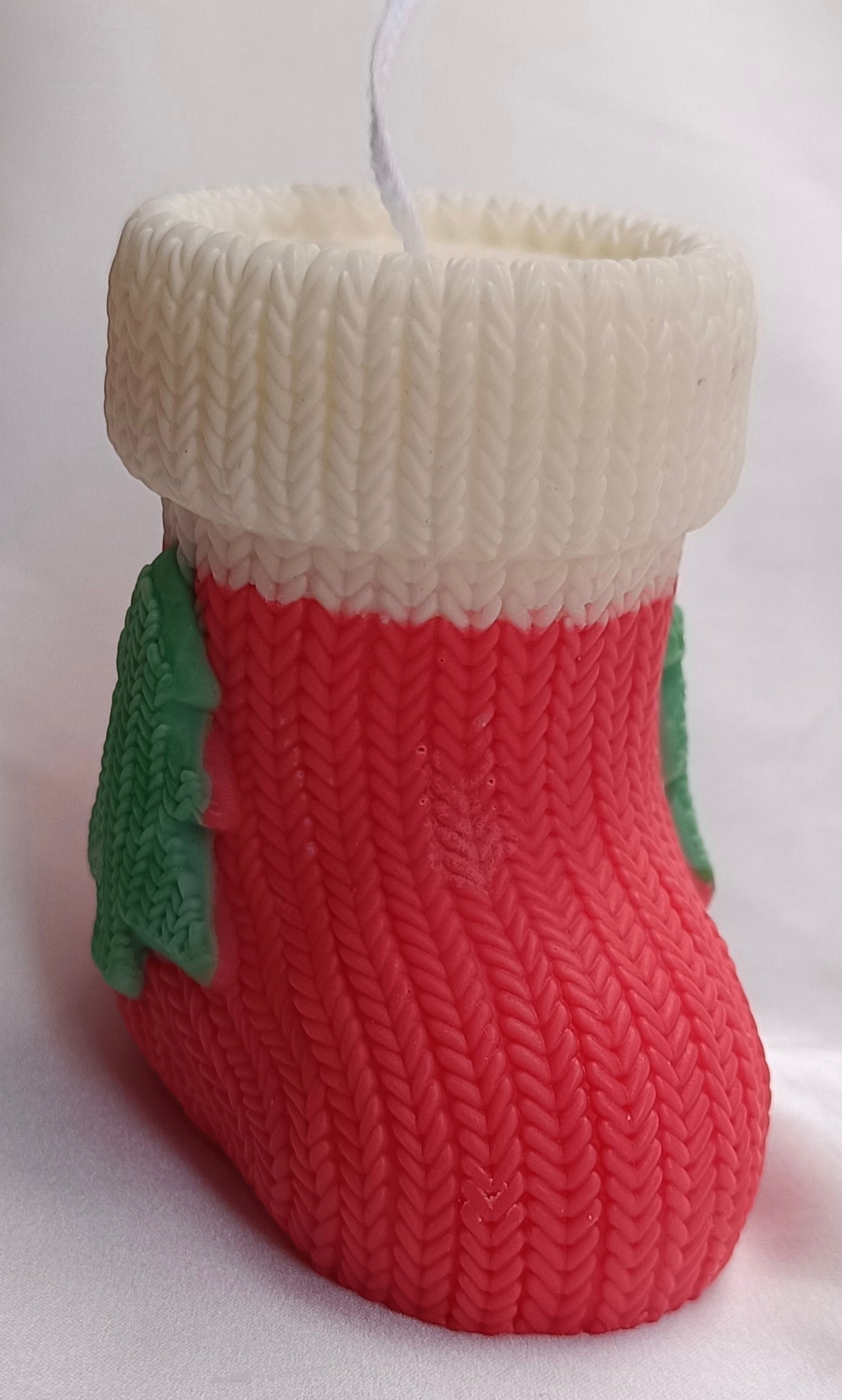 Vista lateral de la vela artesanal Bota de Navidad, mostrando la textura de punto rojo y el detalle verde.