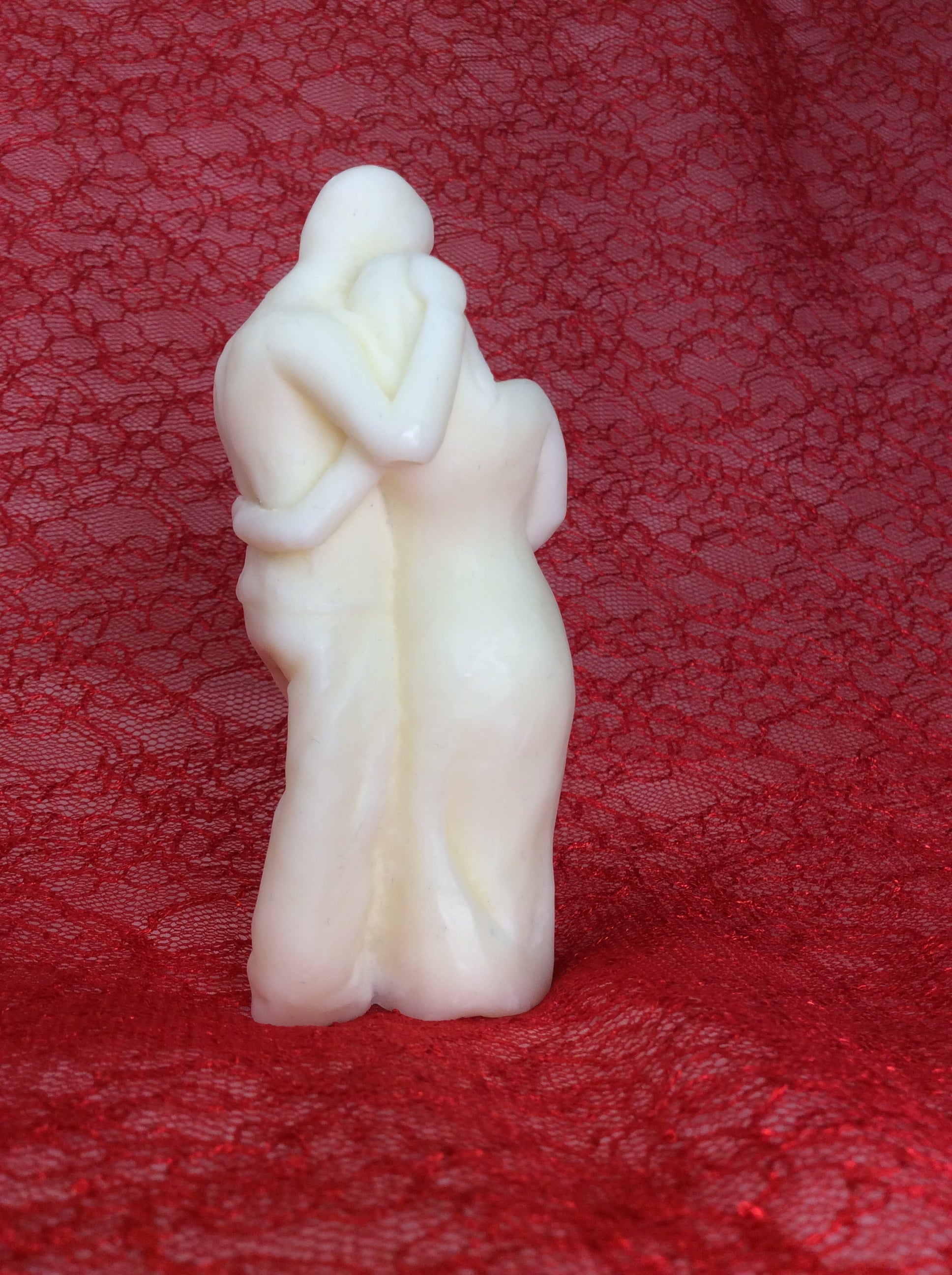 Vista trasera de la vela de pareja embarazada sobre fondo de encaje rojo.