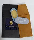 Perfume sólido natural 'Aura Terra' (unisex) en su estuche metálico azul abierto, mostrando la cera perfumada, junto a su funda de antelina.