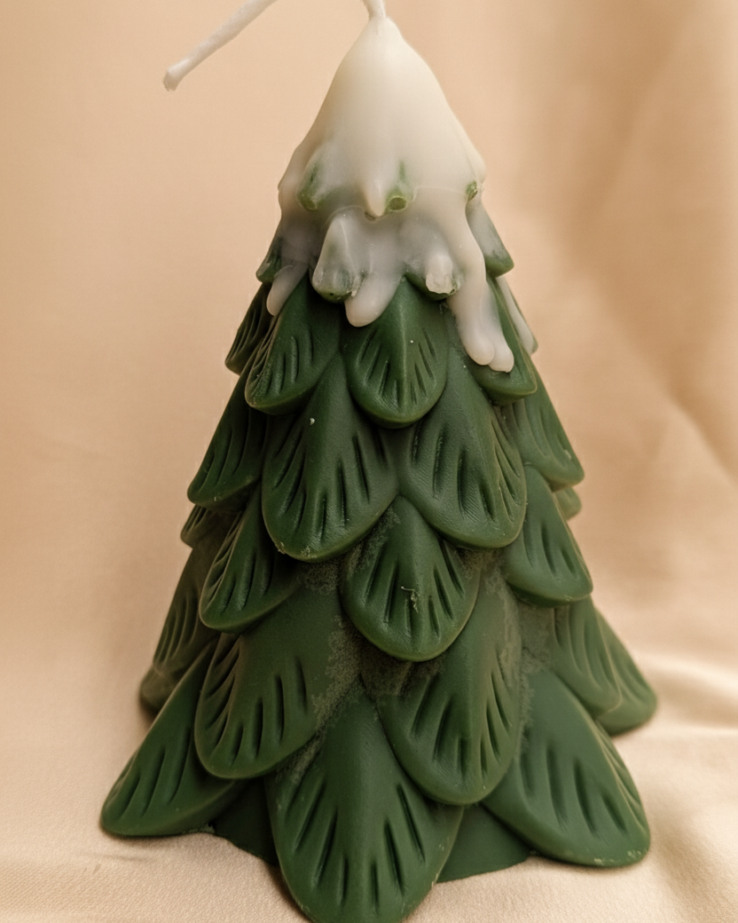 Vela Artesanal Pino Navidad nevado hecha con cera de soja, destacando el color verde pino y el efecto nieve en la punta, sobre un fondo beige champagne.