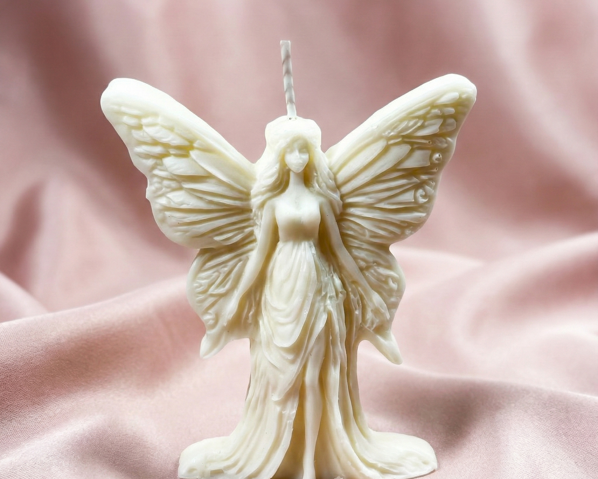 Vela escultural de cera blanca con forma de hada de pie y alas detalladas
