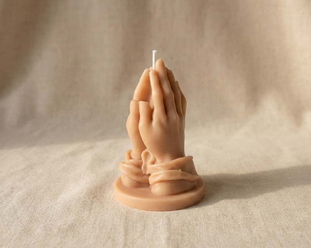 Vela escultural de cera con forma de manos rezando en tono piel beige.