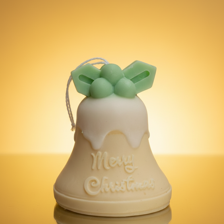 Vela Campana Navidad Acebo en tono crema y verde, con mensaje grabado "Merry Christmas", sobre un fondo dorado claro.