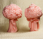 Set de dos velas decorativas con forma de ramo de flores y lazo. Color rosa pastel sobre fondo beige