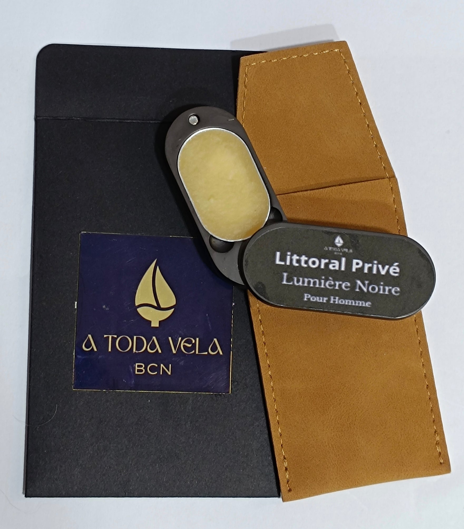 Perfume sólido para hombre 'Lumière Noire' abierto, mostrando la cera perfumada amaderada y mineral, con su funda y packaging.