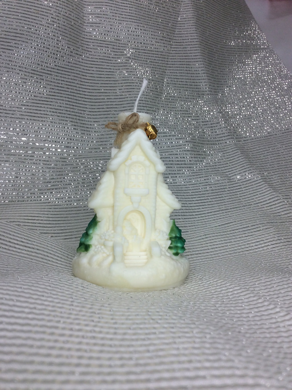 Vela de Navidad con forma de iglesia nevada y un cascabel dorado atado con yute.