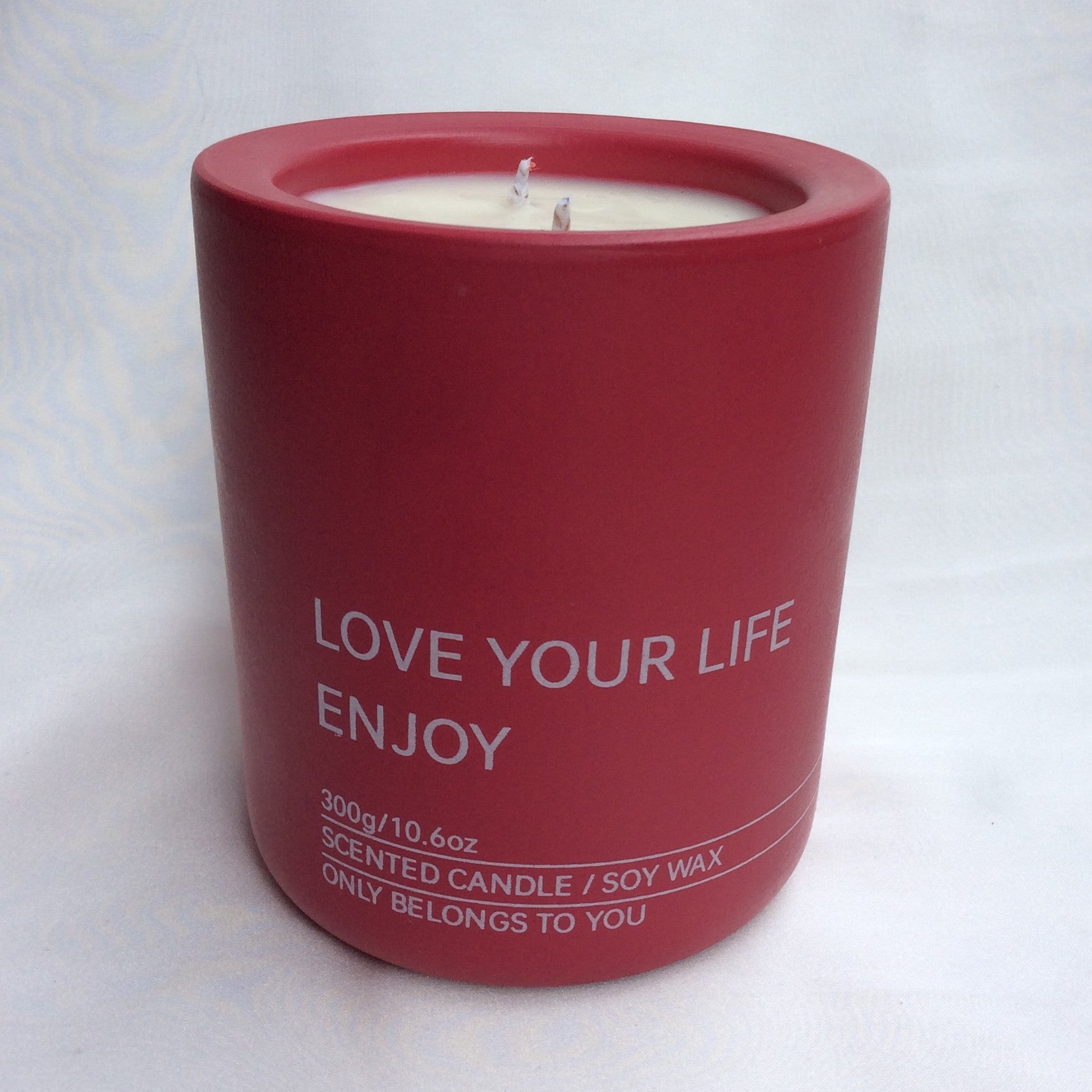 Primer plano de la vela aromática A Toda Vela BCN Rumbo al Alba en recipiente color rojo vibrante con la cera de soja blanca. Se lee "LOVE YOUR LIFE ENJOY" y "300g/10.6oz SCENTED CANDLE / SOY WAX". El envase resalta la cera vegetal ecológica y la doble mecha de algodón para una difusión óptima de la fragancia de Azahar y Bergamota.