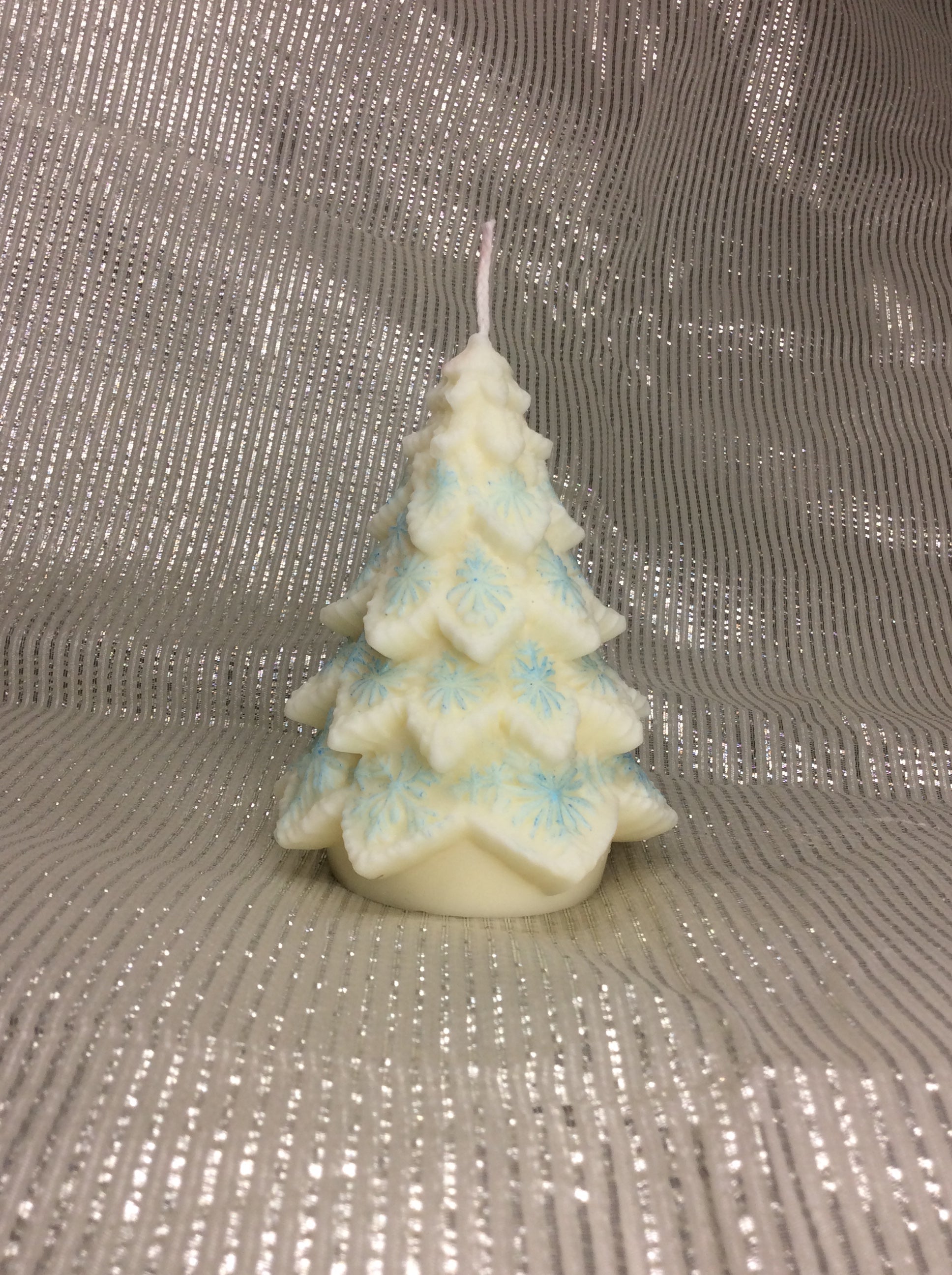 Vela de Navidad con forma de árbol y copos de nieve azules pintados a mano.