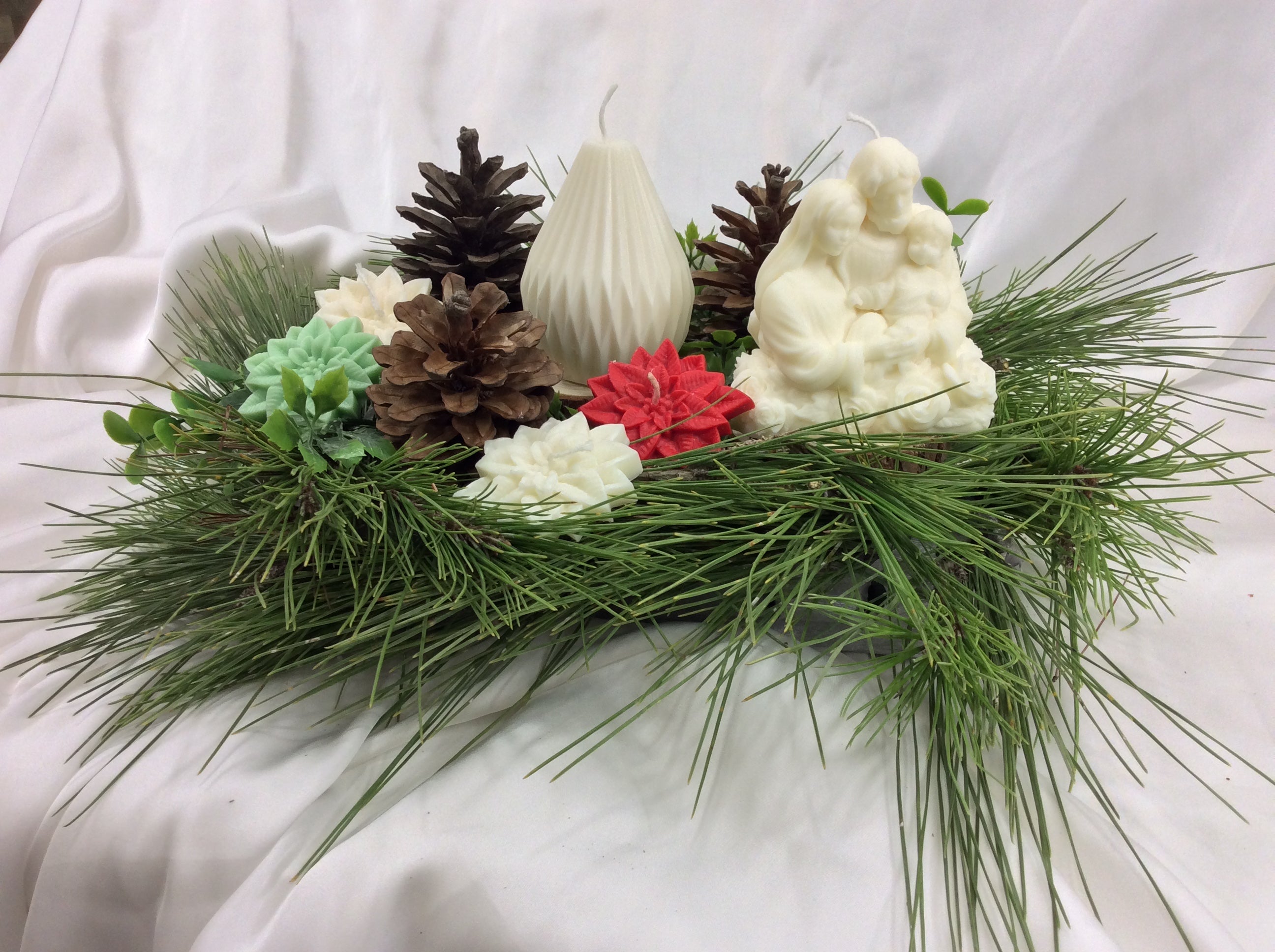 Centro de mesa con velas de la Sagrada Familia y una vela geométrica blanca.