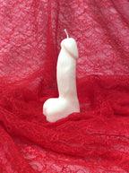 Vela fálica divertida para despedida de soltera sobre fondo de encaje rojo.