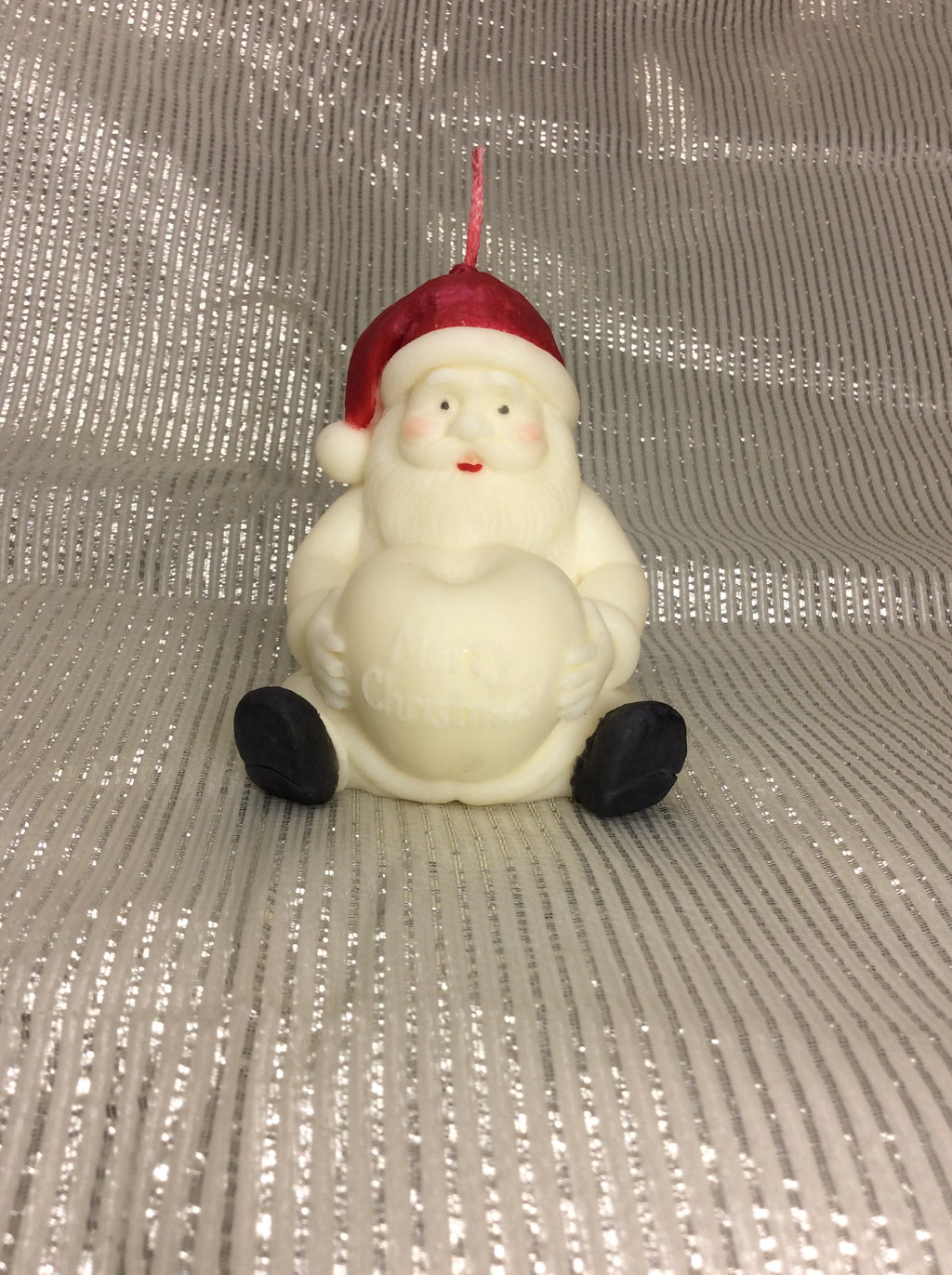 Vela artesanal de Navidad de Santa Claus con corazón sobre fondo plateado.