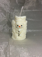 Vela aromática de muñeco de nieve con relieve 3D sobre fondo plateado.