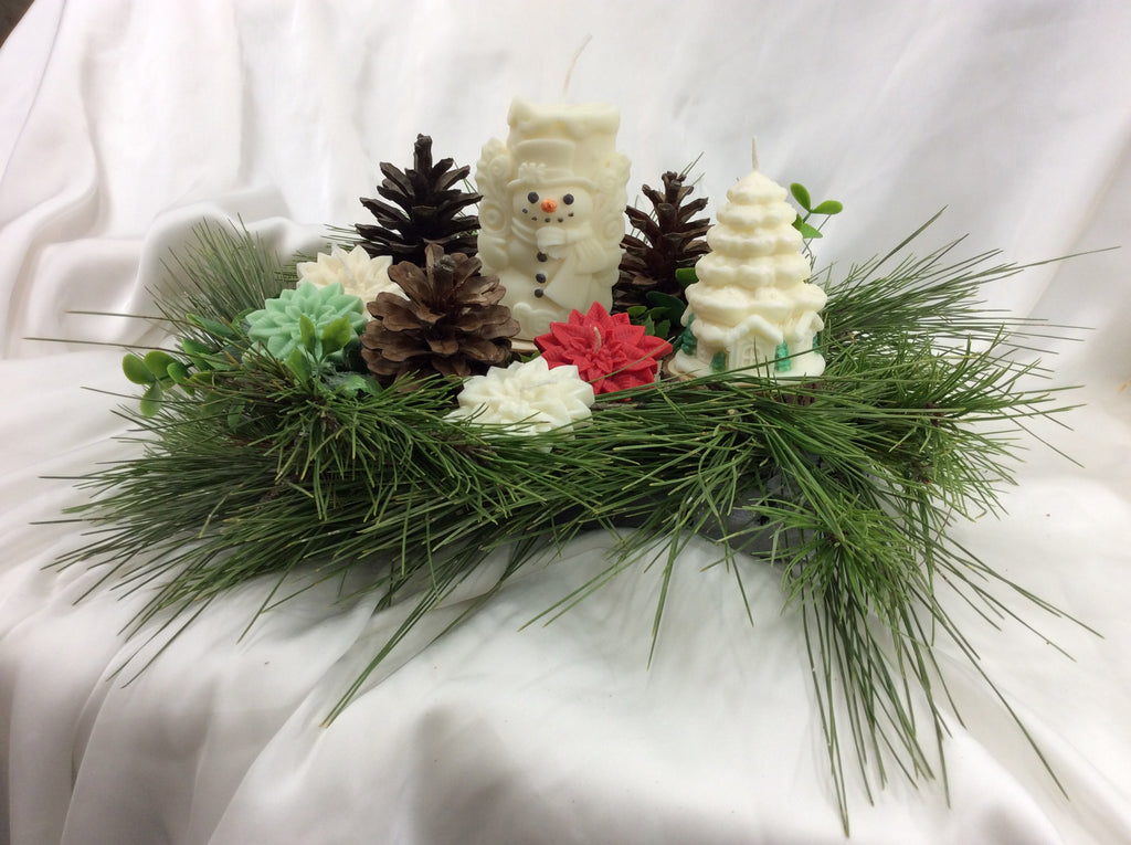 Centro de mesa navideño con vela de muñeco de nieve y pino natural.