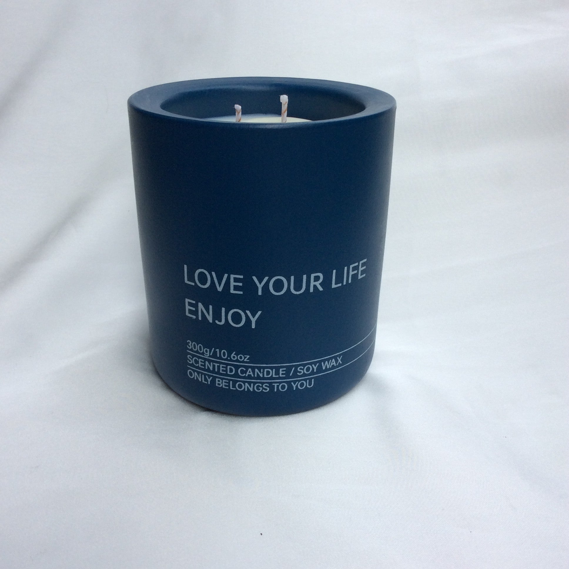 Primer plano de la vela ecológica A Toda Vela BCN Rumbo al Horizonte en tarro azul marino. Se distinguen el logo y el texto "SCENTED CANDLE / SOY WAX 300g". La vela de cera vegetal 100% ecológica y mecha de algodón representa la fragancia fresca, mineral y profunda inspirada en el mar, con notas de Ámbar Solar y Cedro.