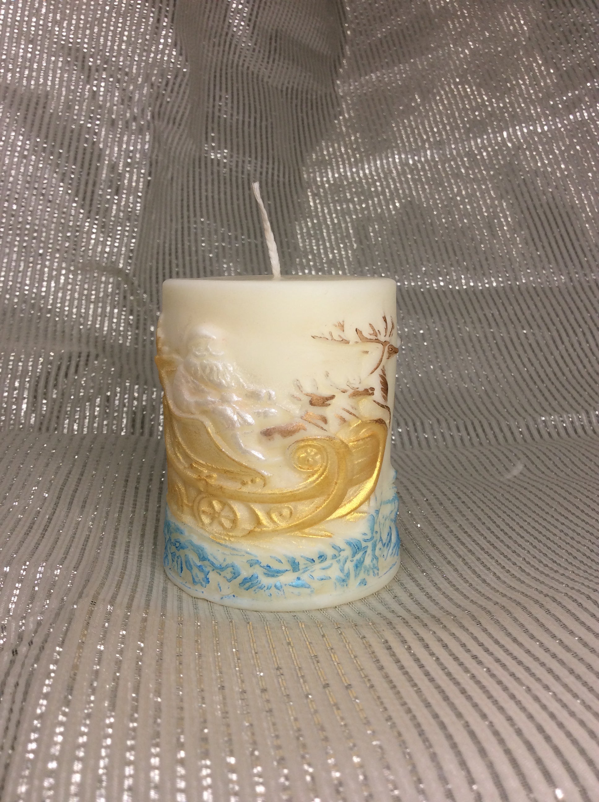 Vela Papá Noel Trineo, detalle del Papá Noel en el trineo dorado, con renos y base azul nevada.