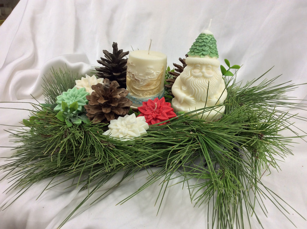 Vela de Papá Noel con gorro verde junto a una vela cilíndrica con relieve.