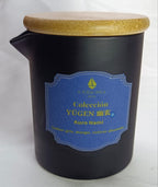 Vela de masaje Yūgen 'Kuro Nami' con tapa de madera, para un ritual de introspección con aroma a ambar gris, musgo y vetiver ahumado.