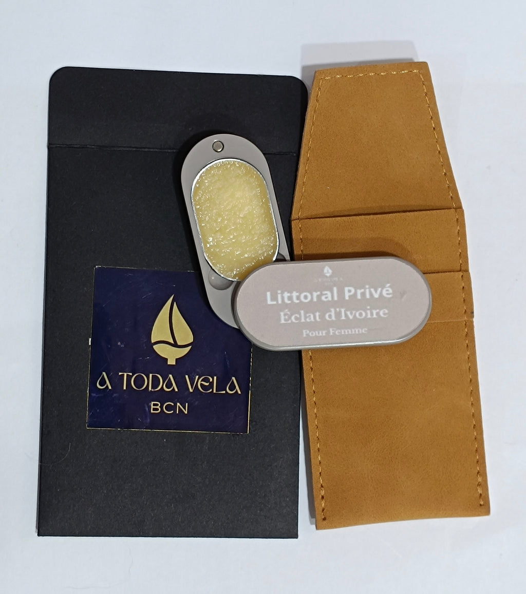 Perfume sólido natural 'Éclat d'Ivoire' (femenino) en su estuche metálico nude abierto, mostrando la cera perfumada floral, junto a su funda de antelina.