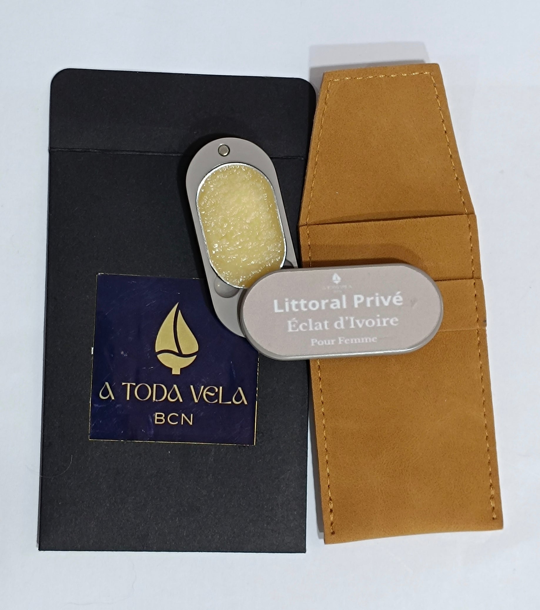 Perfume sólido natural 'Éclat d'Ivoire' (femenino) en su estuche metálico nude abierto, mostrando la cera perfumada floral, junto a su funda de antelina.