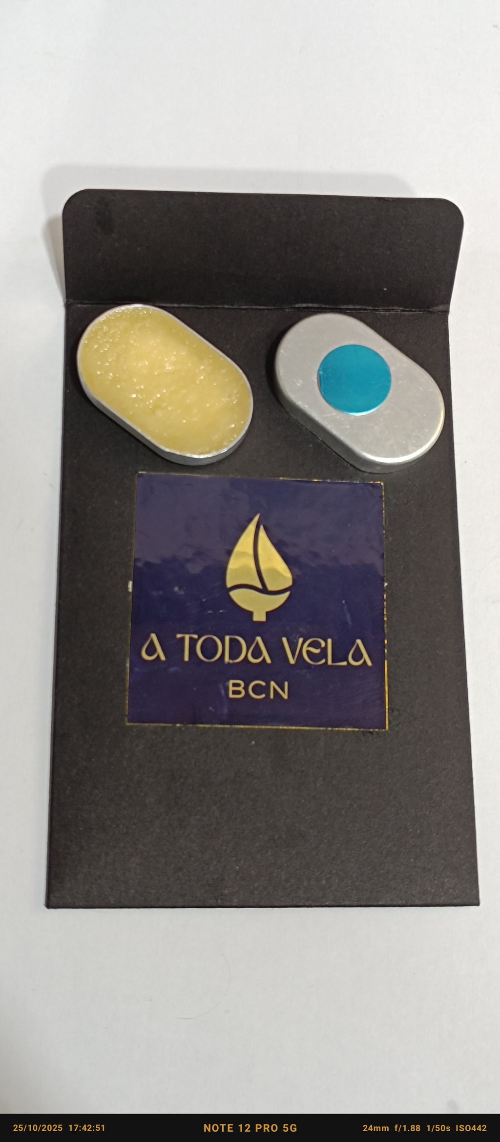 Sistema recargable de perfume sólido artesanal con dos compartimentos en estuche metálico negro.
