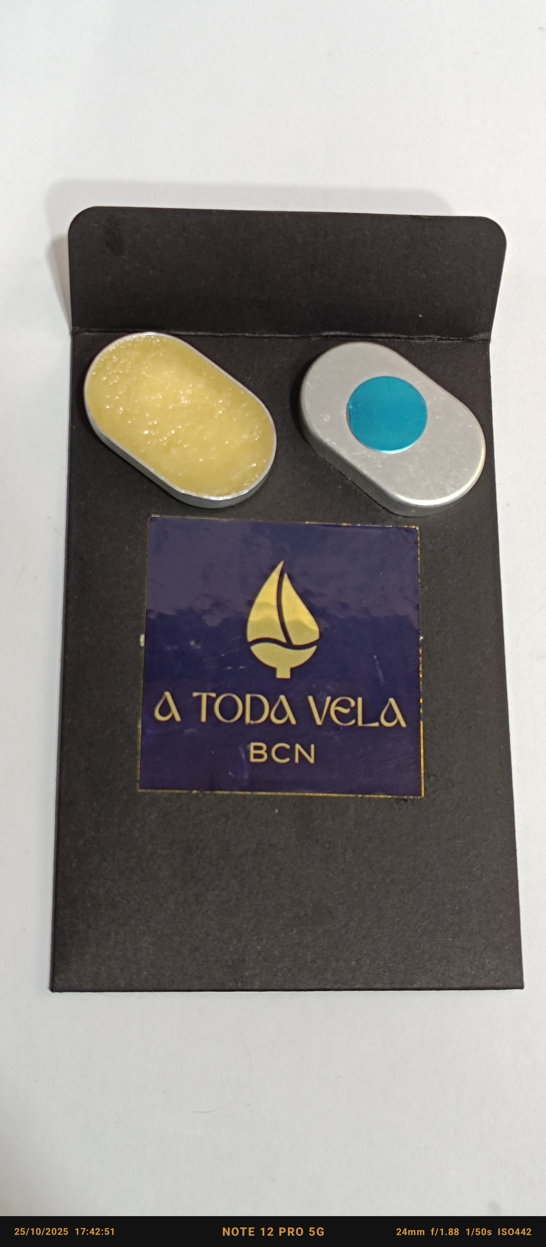 Sistema recargable de perfume sólido artesanal con dos compartimentos en estuche metálico negro.
