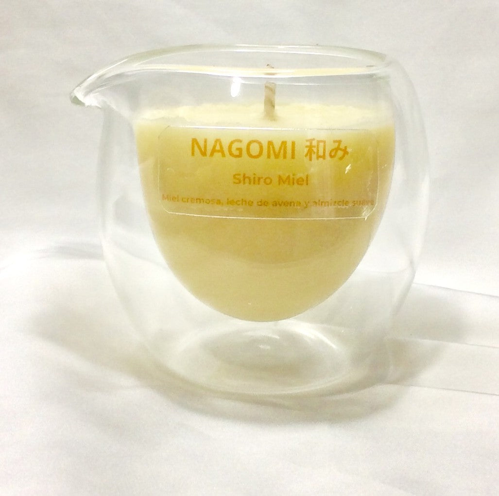 Aceite tibio de la vela de masaje Nagomi 'Shiro Miel', listo para un masaje suave y reconfortante de cera natural.