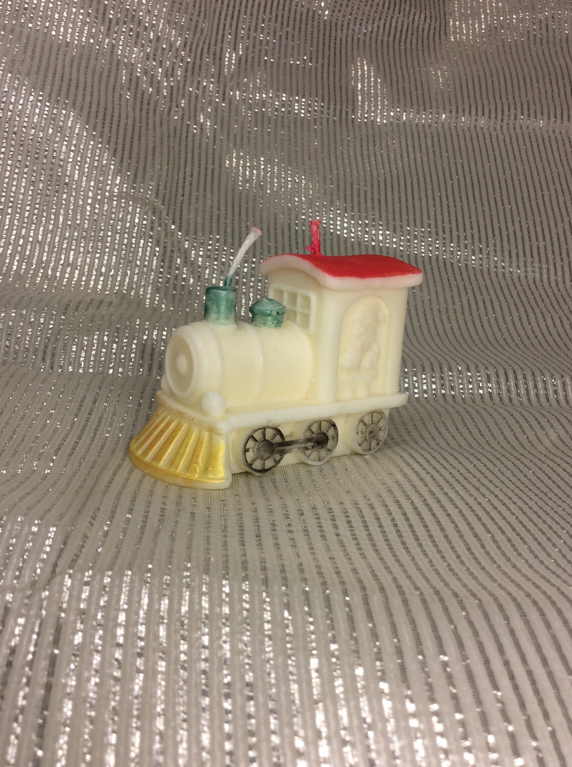 Vela de Navidad con forma de locomotora de tren, pintada a mano en rojo y dorado.