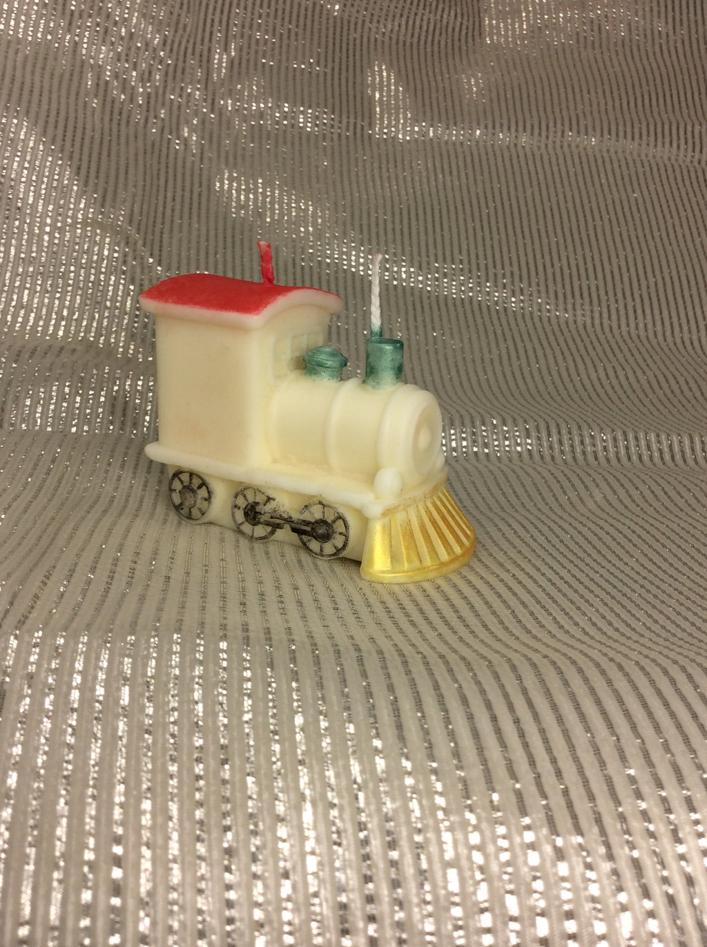 Vela de cumpleaños de tren artesanal con detalles pintados sobre fondo plateado.