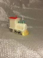 Vela de cumpleaños de tren artesanal con detalles pintados sobre fondo plateado.