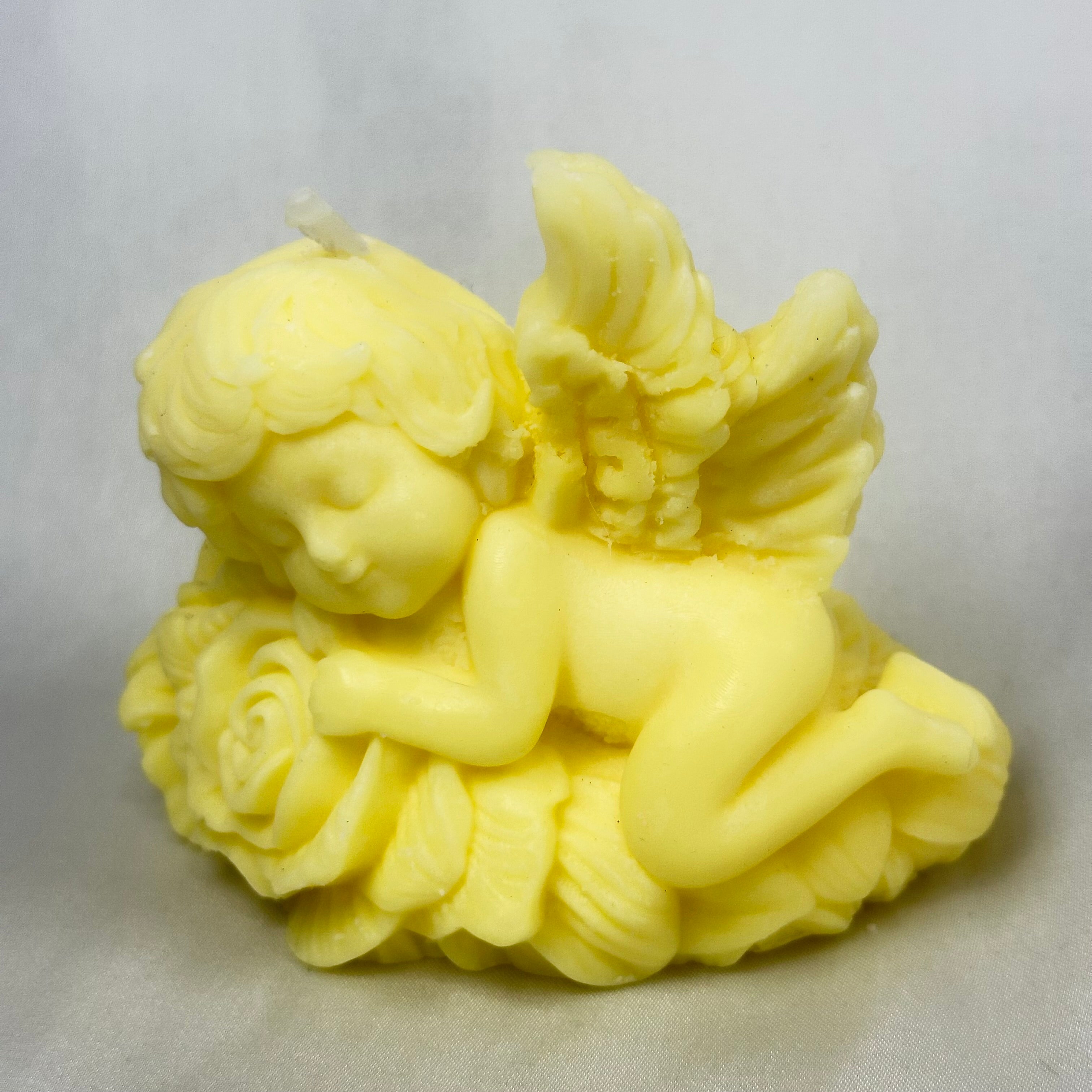 Vela de bautizo artesanal ecológica con figura de ángel durmiendo, símbolo de protección."