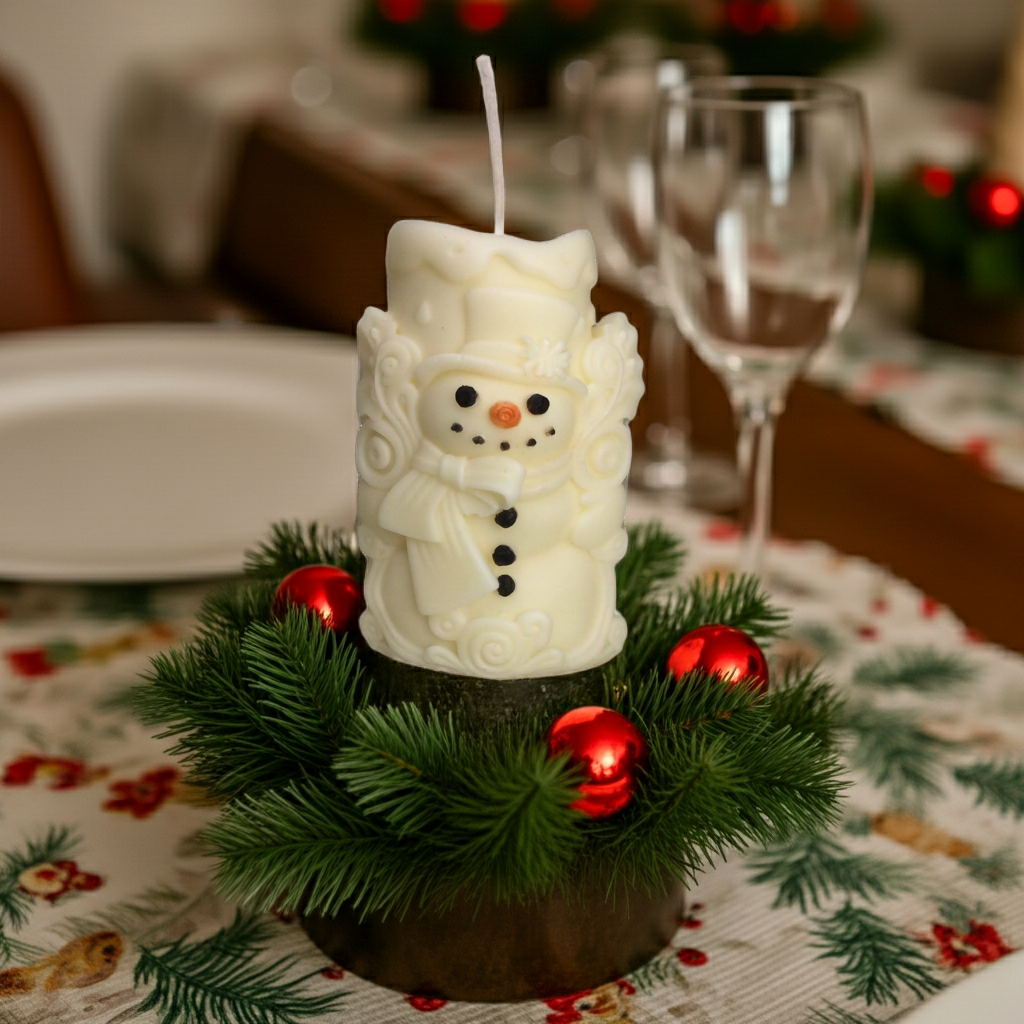 Vela de muñeco de nieve decorando una mesa de Navidad junto a un chocolate caliente.