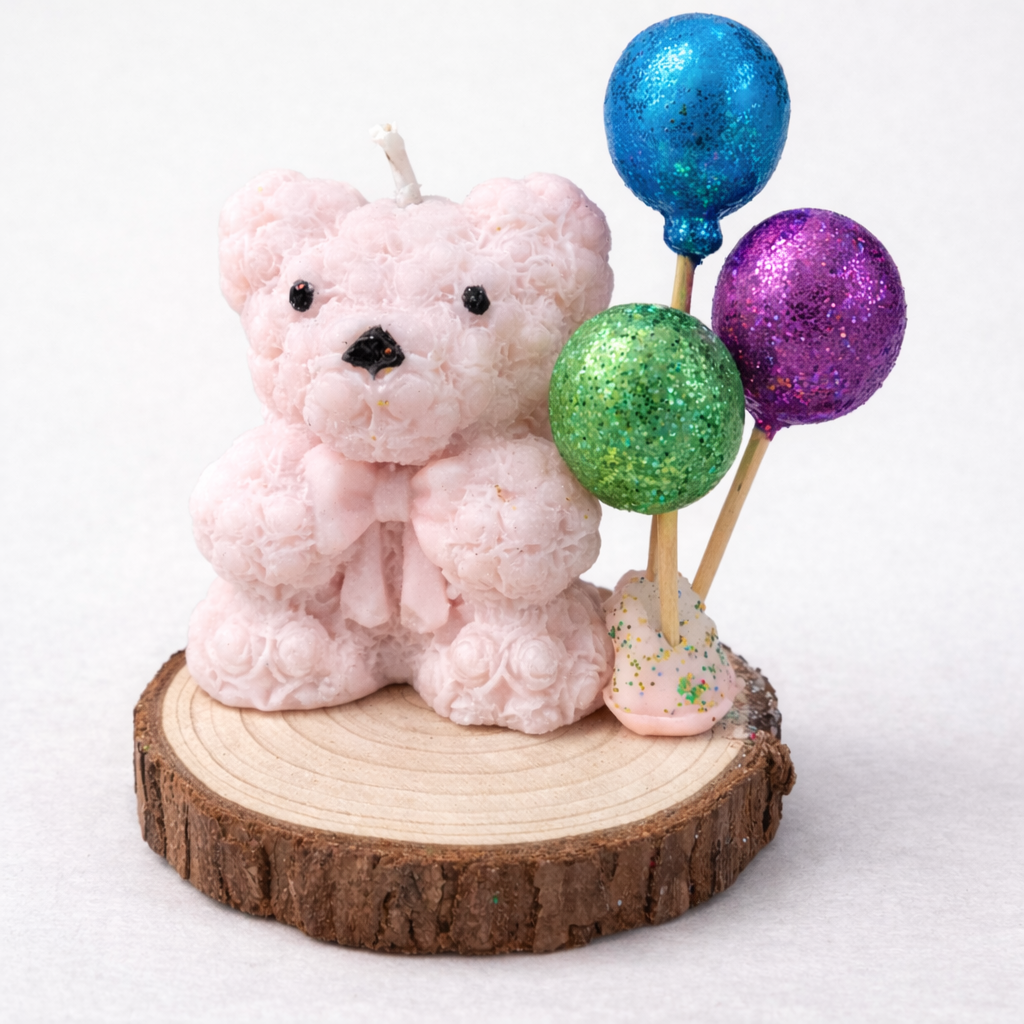 Vela artesanal de bautizo con osito rosa y globos decorativos azul, verde y púrpura sobre base de madera